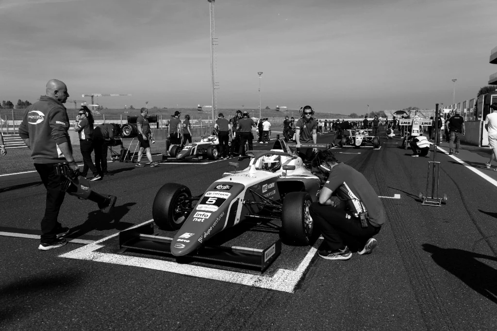 Formula car on the grid with the team around it.