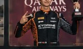 Driver on the podium with a trophy.